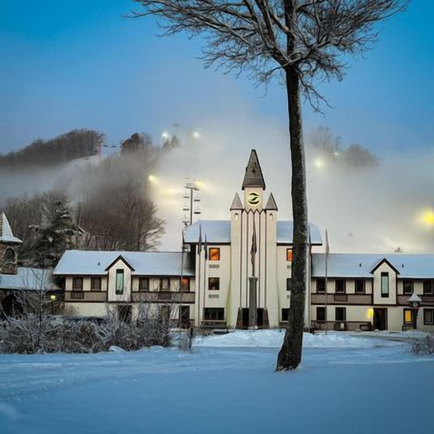 A building with a central tower, multiple windows, and a snow-covered roof.
