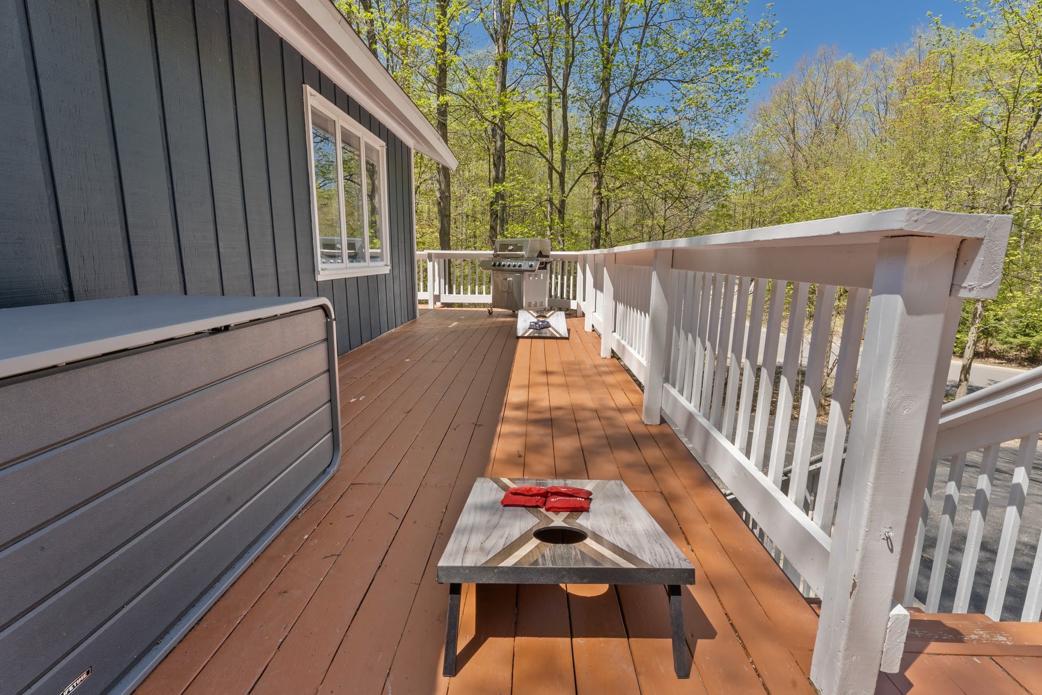 Une terrasse en bois avec un barbecue et une table agrémentée de serviettes rouges.