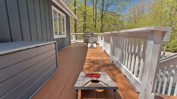 Une terrasse en bois avec un barbecue et une table agrémentée de serviettes rouges.