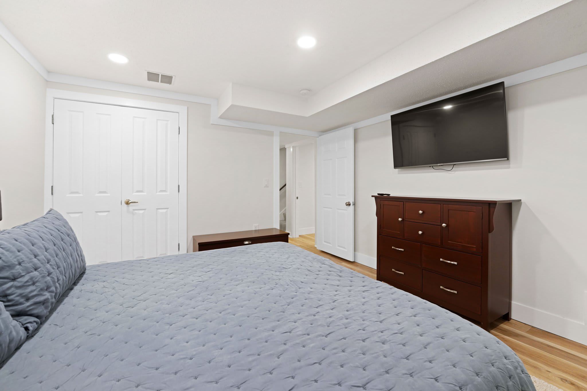 Une chambre à coucher avec un lit, une commode, un téléviseur et une porte.