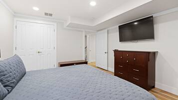 Une chambre à coucher avec un lit, une commode, un téléviseur et une porte.