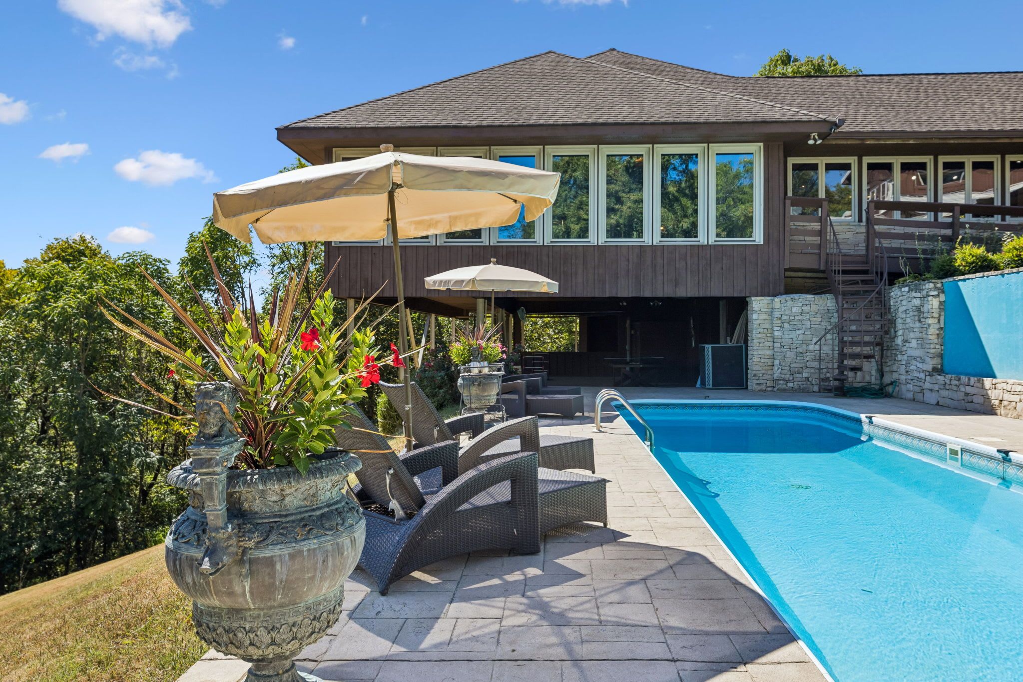 A modern house with a swimming pool, outdoor furniture, and potted plants.
