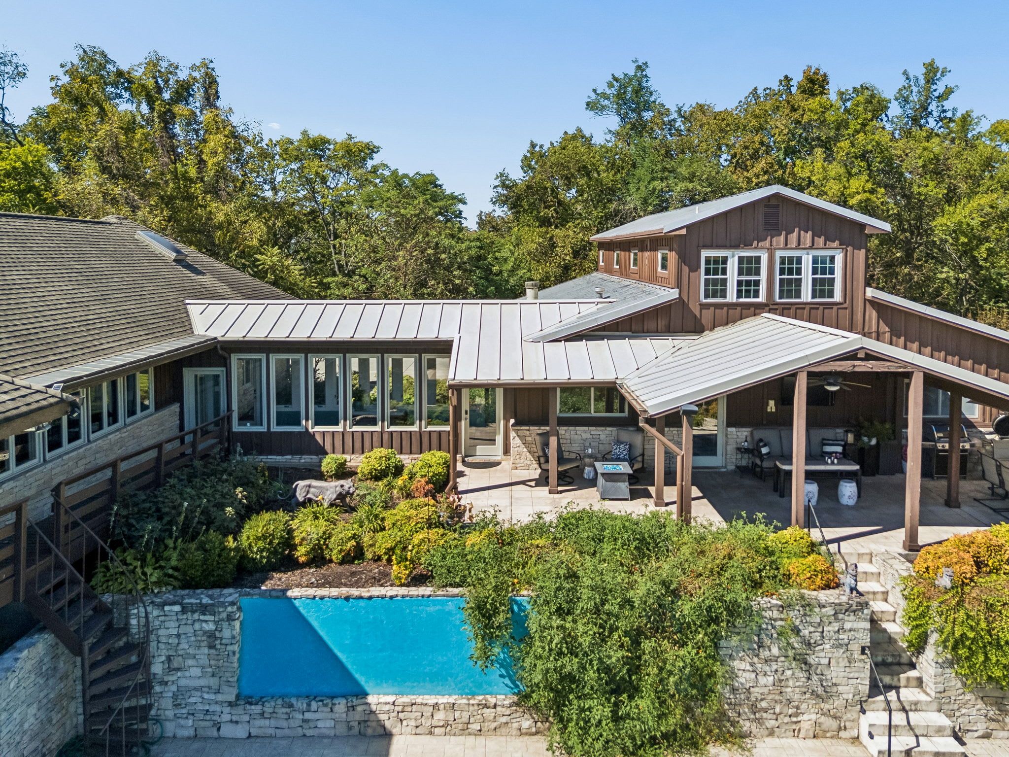 A two-story house with a swimming pool, outdoor seating, and a covered patio.