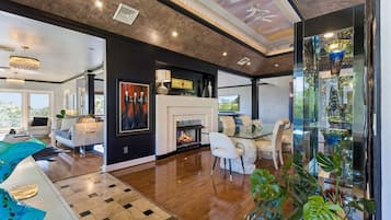 A modern living room with a fireplace, a dining area, and a view of the outdoors.