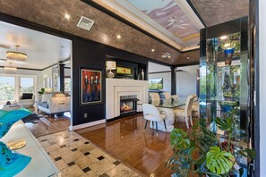 A modern living room with a fireplace, a dining area, and a view of the outdoors. - Breathtaking mountain-view home w/ exclusive pool! (Goodlettsville)