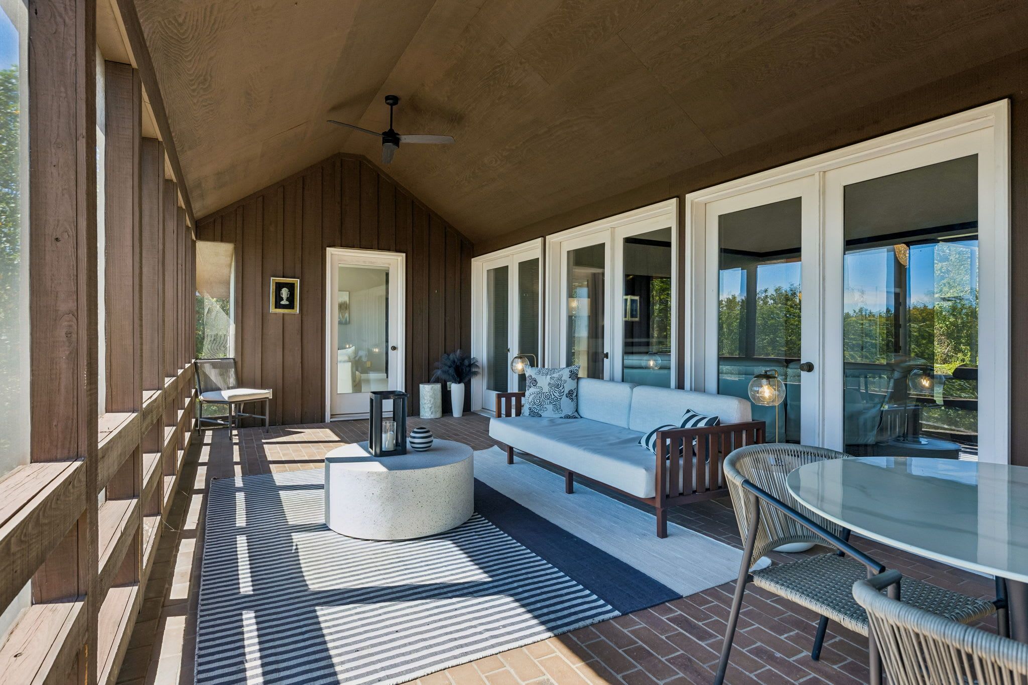 A covered outdoor seating area with a sofa, chairs, and a table.