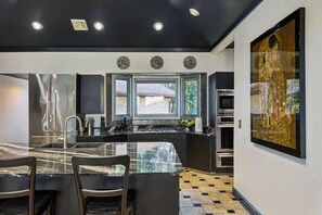 A modern kitchen with a central island, built-in appliances, and a large window. - Breathtaking mountain-view home w/ exclusive pool! (Goodlettsville)