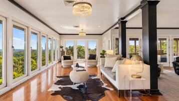 A spacious room with large windows, a wooden floor, a black and white rug, and modern furniture.