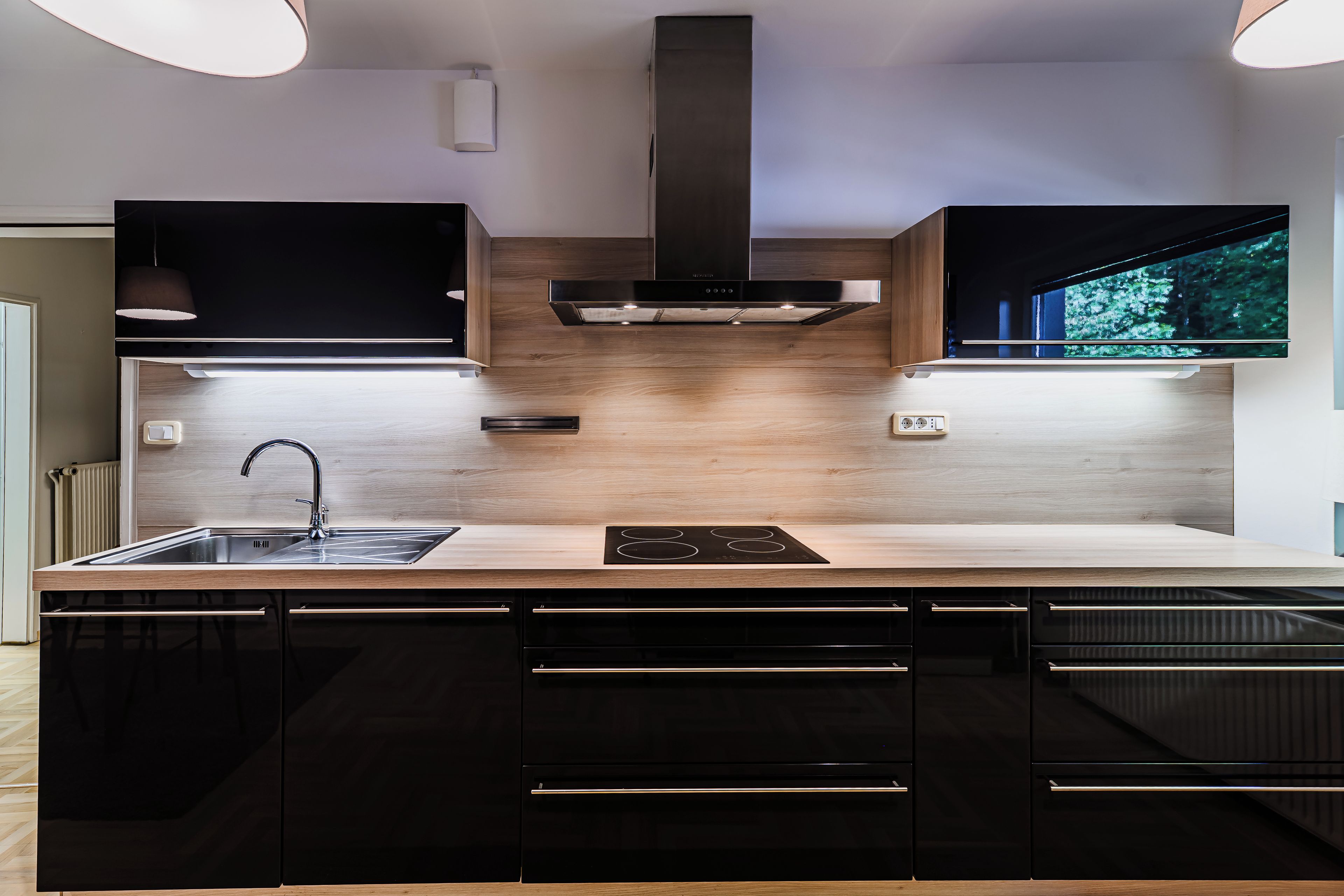 A modern kitchen with a built-in stove, a sink, and black cabinetry.
