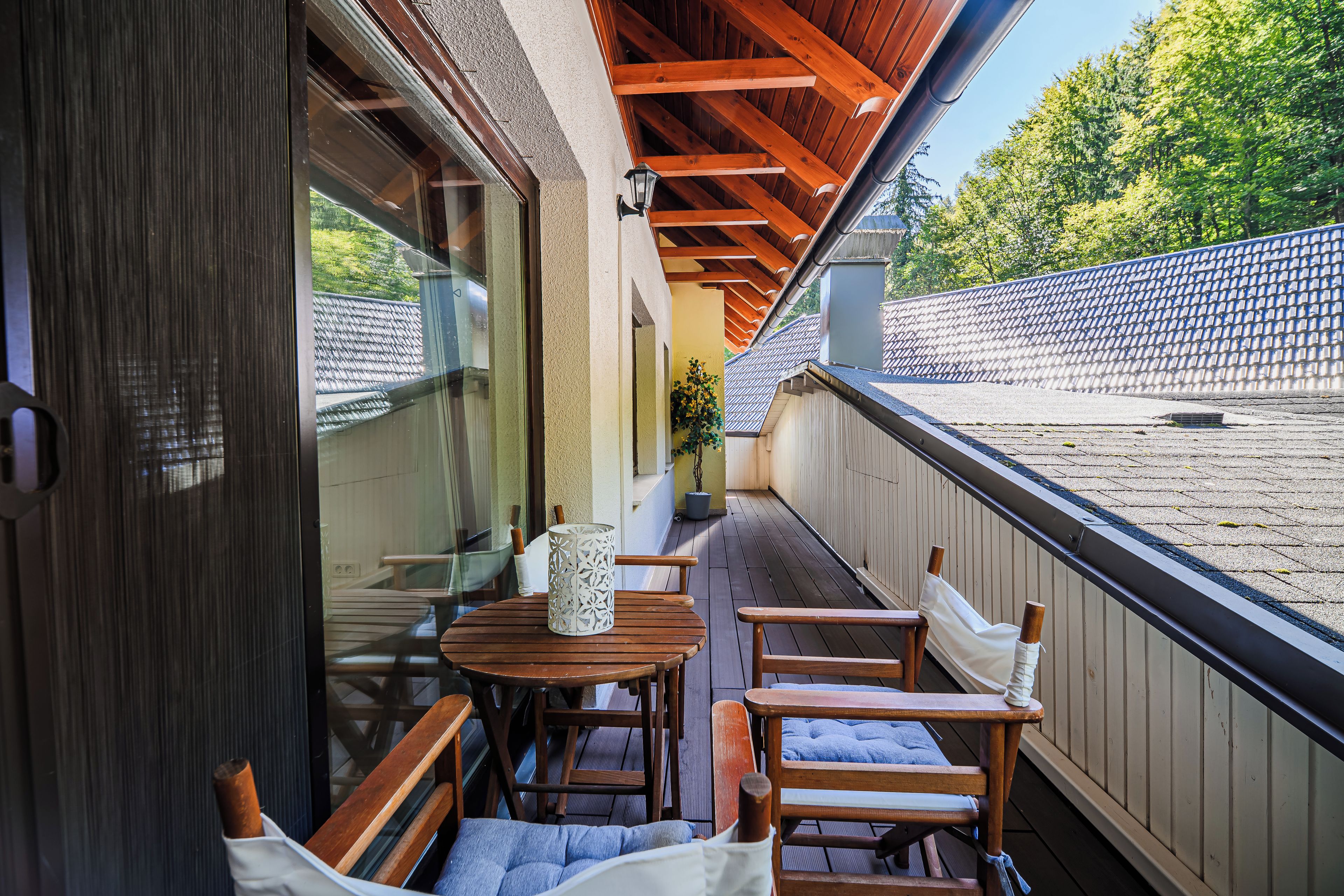 A balcony with wooden furniture, a table, and chairs.