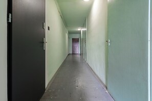 Ein langer, schmaler Flur mit Türen an beiden Seiten, der zu einem Raum mit einer violetten Tür am Ende führt.