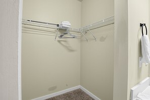 Eine Raumecke mit einer beigen Wand, einem weißen Boden und einem Metalltrockner mit einem Handtuch.