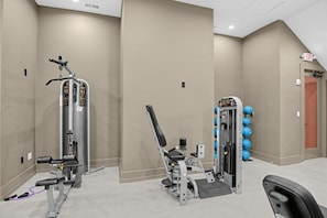 A gym with cardio and strength training equipment, a wall-mounted rack with blue exercise balls, and an exit sign. - Aggieland Stay with Pool and  Perfect for Game Days (College Station)