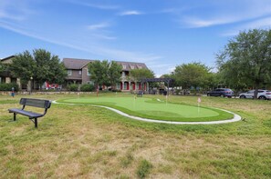 A residential area with a small green space featuring a putting green and a bench. - Game Day Getaway Near Texas A&M with Pool (College Station)