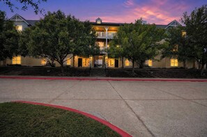 A hotel with a central entrance, multiple windows, and a red curb. - Game Day Getaway Near Texas A&M with Pool (College Station)