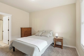 A bedroom with a bed, a nightstand, a dresser, and a door. - Game Day Home Base with Pool and Near Texas A&M (College Station)