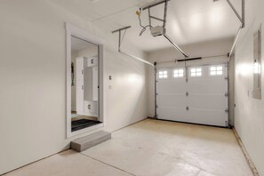 Eine Garage mit einer weißen Tür, einem Betonboden und Metallbefestigungen an der Decke.