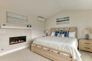 Ein Schlafzimmer mit einem Bett, einem Kamin, einem Nachttisch, einer Lampe und Wandbildern.