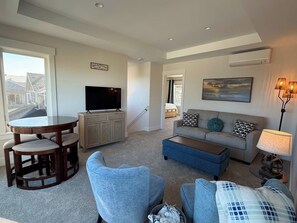 Ein Wohnzimmer mit einer Couch, einem Couchtisch, einem Fernseher und einem Essbereich mit Stühlen und einem Tisch.