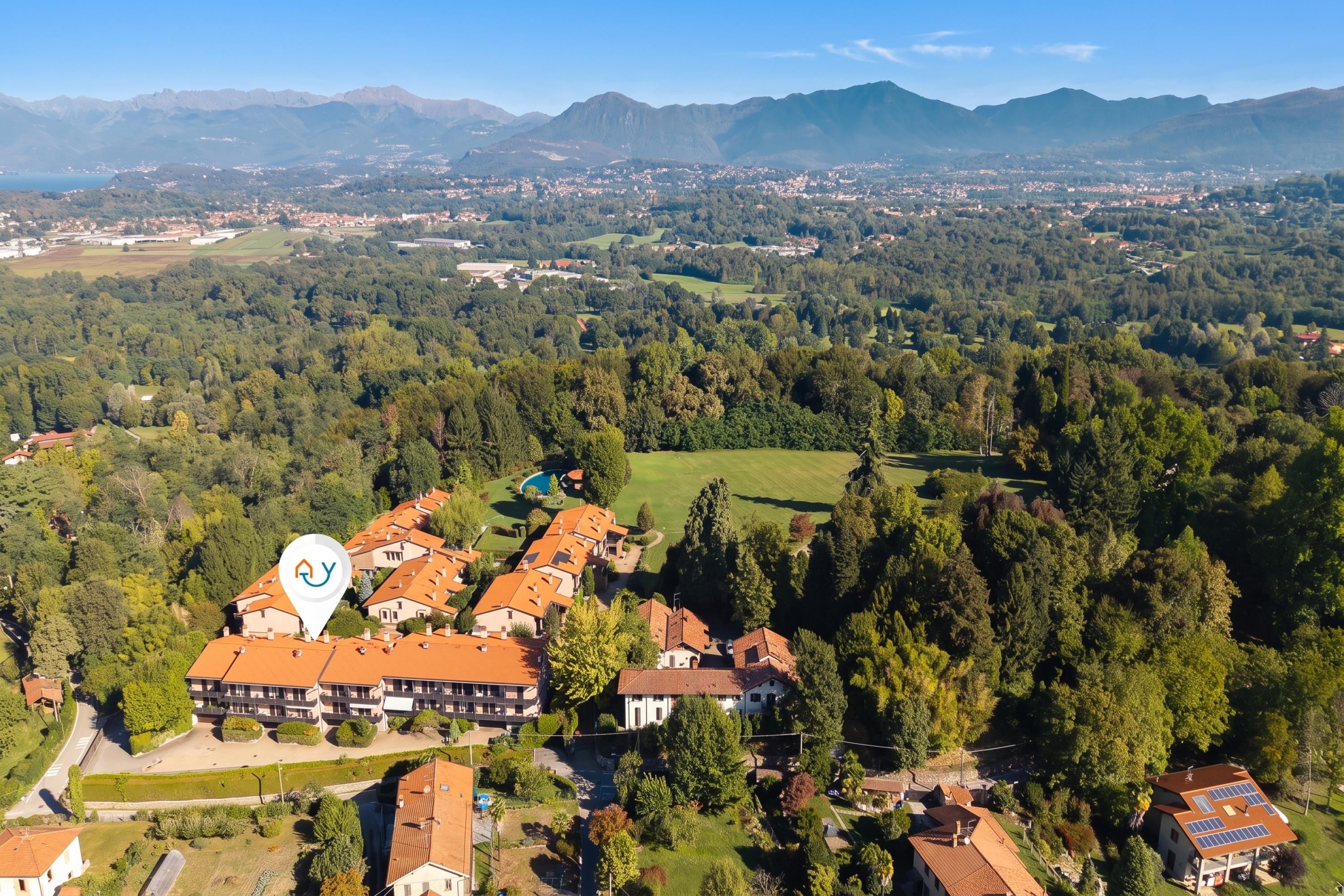 Un quartiere residenziale con diverse case, una piscina e un edificio di grandi dimensioni con un tetto caratteristico.