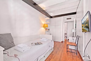 A modern bedroom with a bed, bedside tables, a lamp, a chair, and a TV mounted on the wall. - Borgo Della Motta Swimming Pool &golf (Travedona-Monate)