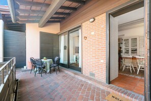 A patio with a table and chairs, a door leading to a kitchen, and a welcome mat. - Borgo Della Motta Swimming Pool &golf (Travedona-Monate)