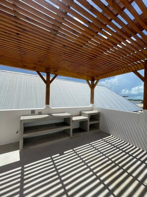 A covered outdoor area with a wooden ceiling, white walls, and a metal roof. - Pwani House (San Pedro)