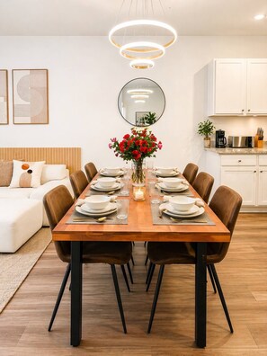 Une salle à manger moderne avec une table en bois dressée pour six personnes, entourée de chaises marron.