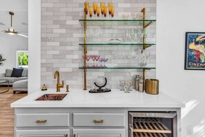 A kitchen with a white countertop, a gold faucet, and a glass shelf with various glassware. - La Quinta Desert Escape | Private Pool | Monthly Stay (La Quinta)