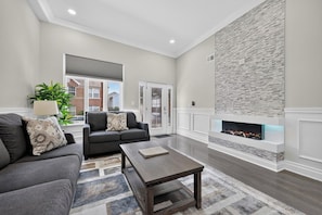 A modern living room with a fireplace, two sofas, a coffee table, and a large window.
