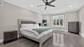 A bedroom with a bed, nightstands, a dresser, a ceiling fan, and a window.