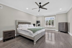 A bedroom with a bed, nightstands, a dresser, a ceiling fan, and a window.
