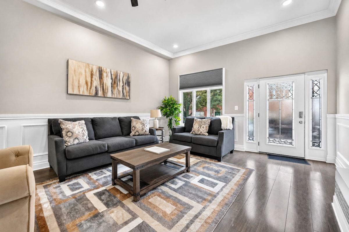 A spacious living room with two sofas, a coffee table, and a large abstract painting on the wall.