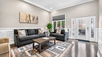 A spacious living room with two sofas, a coffee table, and a large abstract painting on the wall.