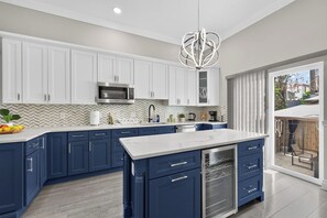 A modern kitchen with white cabinets, a central island, and a stainless steel range hood.