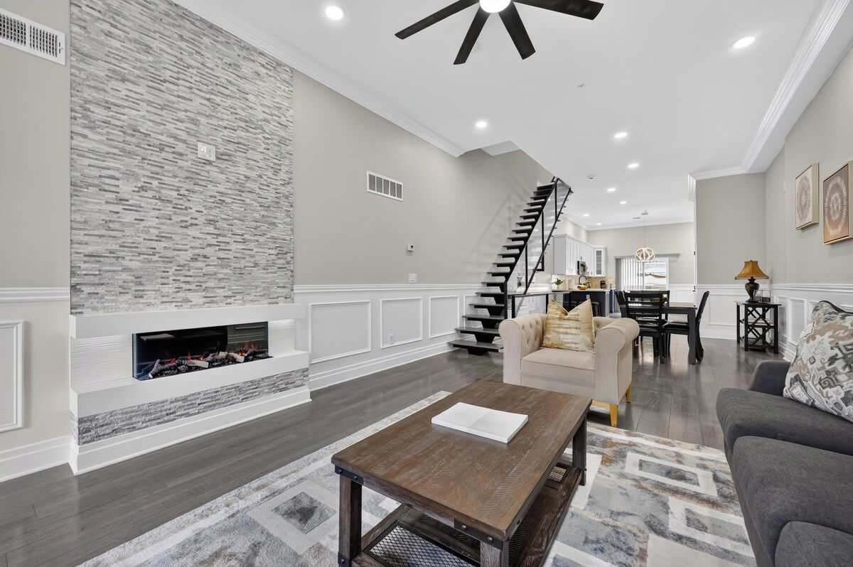 A spacious living area with a fireplace, a staircase, and a dining area.