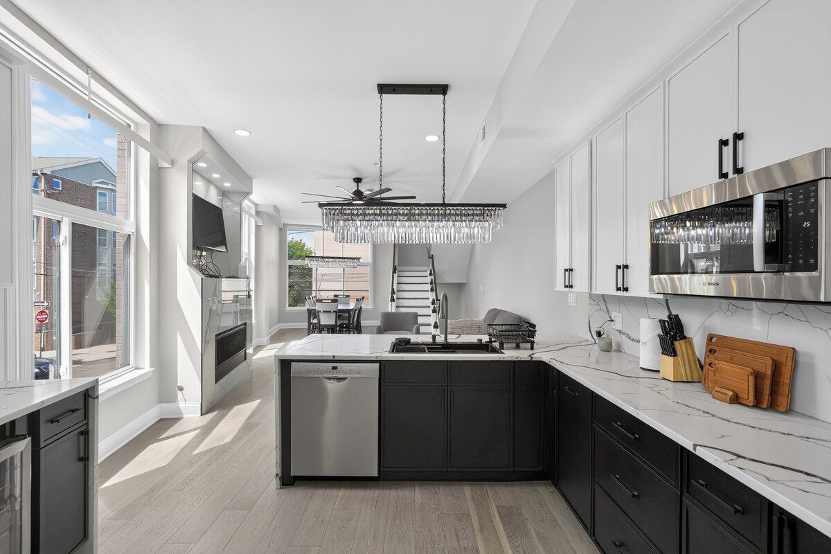 A modern kitchen with a central island, stainless steel appliances, and a chandelier.