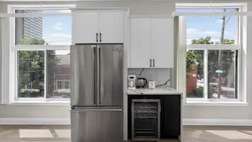 Una cocina moderna con refrigerador de acero inoxidable, armarios blancos y horno empotrado.