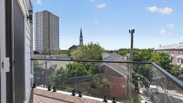 A balcony with a view of a church steeple and residential buildings.