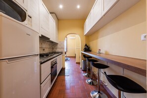 A kitchen with white cabinets, a black countertop, and a red-tiled floor. - Sunflower Suite by MMega Homes and Villas (Florence)
