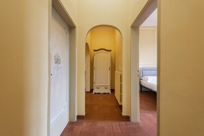 A narrow hallway with a white wardrobe and a bed in the distance. - Sunflower Suite by MMega Homes and Villas (Florence)