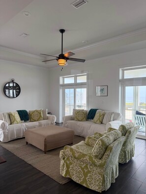 A spacious living room with a ceiling fan, large windows, and a view of the outdoors. - Seas The Day Navarre (Navarre)