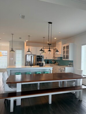 A modern kitchen with white cabinetry, a central island, and pendant lighting. - Seas The Day Navarre (Navarre)