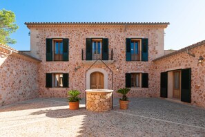Un bâtiment doté d’une cour intérieure, de murs en pierre et de nombreuses fenêtres équipées de volets.