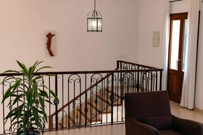 Eine Treppe mit Geländer, einer Hängelampe, einem Blumentopf und einer Tür mit Vorhängen.