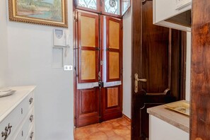 A room with a wooden door, a white wall-mounted telephone, and a tiled floor. - GuestHost - Cozy Apartment in Downtown Turin (Turin)