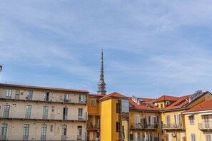 Eine Reihe von mehrstöckigen Gebäuden mit Balkonen, ein markanter Turm und ein klarer Himmel.