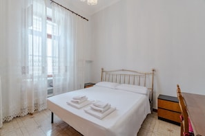 A bedroom with a bed, nightstands, a wooden dresser, and sheer curtains. - GuestHost - Cozy Apartment in Downtown Turin (Turin)