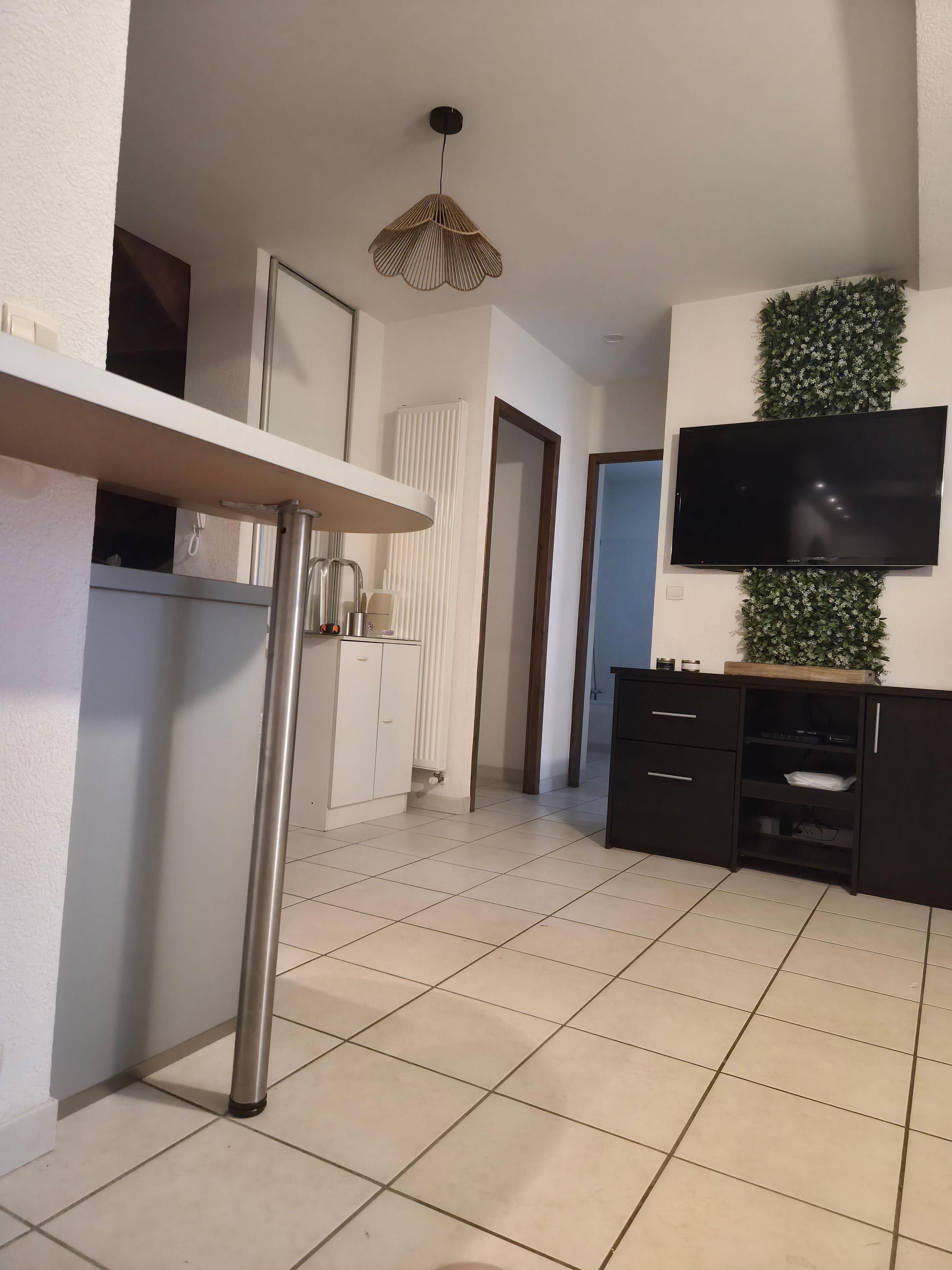 Een moderne keuken met een wit aanrechtblad, een zwarte kast en een flatscreen televisie aan de muur.