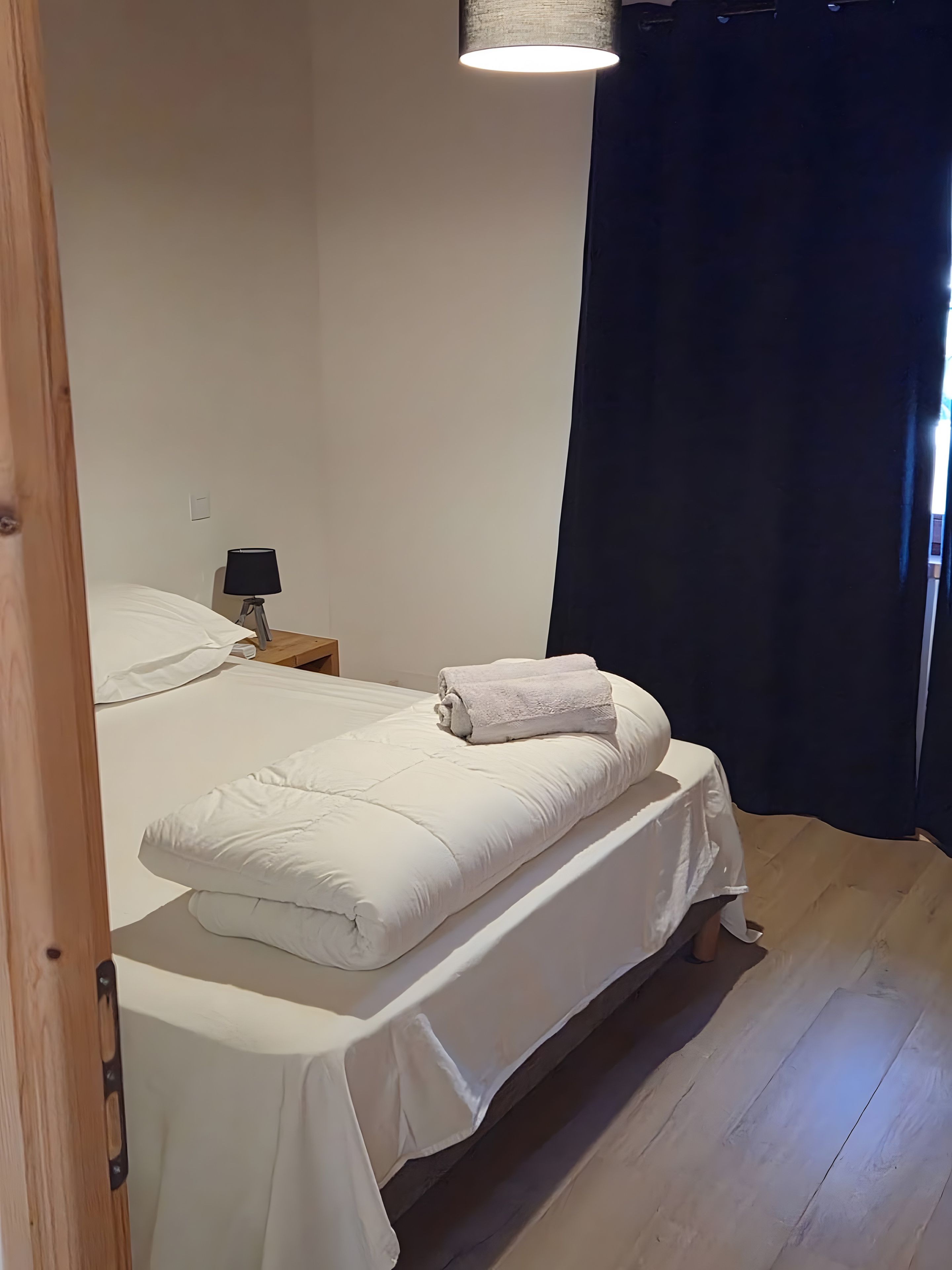 Un dormitorio con una cama, una mesita de noche y una lámpara.